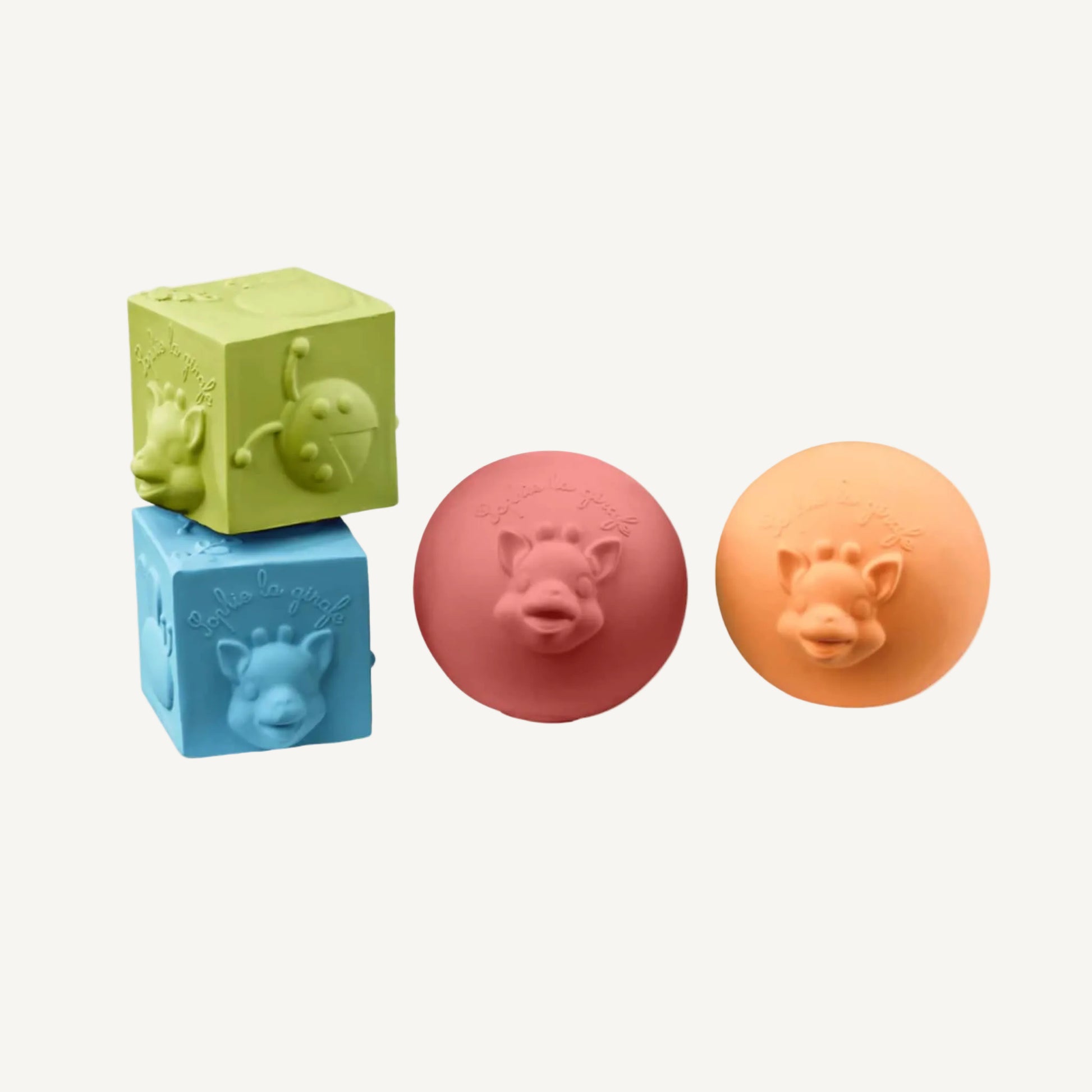 A set of soft natural rubber sensory toys including two textured cubes stacked together and two round balls with raised giraffe face details.