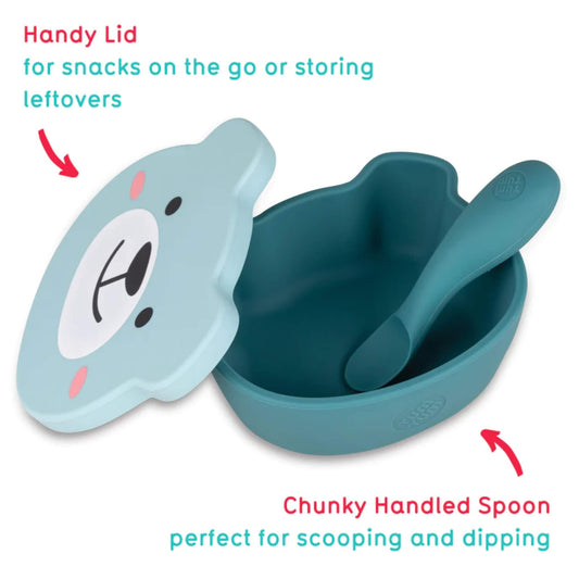 Blue silicone baby suction bowl shown open with bear-shaped lid resting beside bowl and chunky handled spoon inside.
