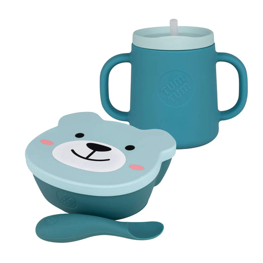 TUM TUM suction bowl and trainer cup bundle shown together on a white background, including a handled trainer cup, matching suction bowl with fitted lid, and soft weaning spoon.