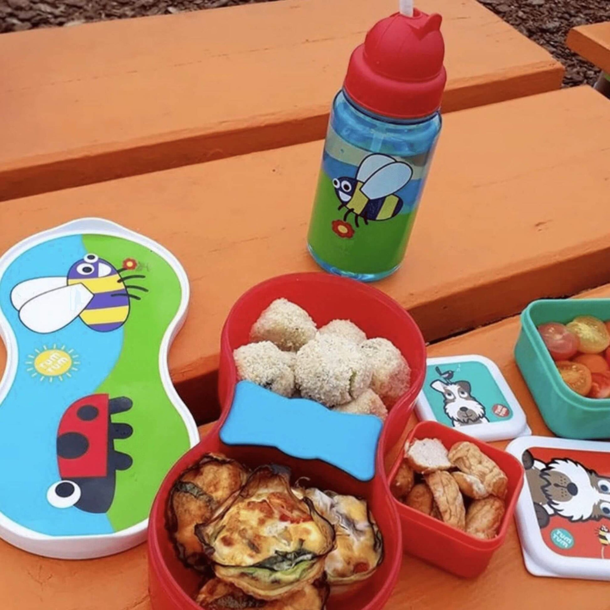 A children's water bottle with bugs design alongside snack pots and lunchbox, perfect for kids' meals and keeping drinks leakproof on the go.