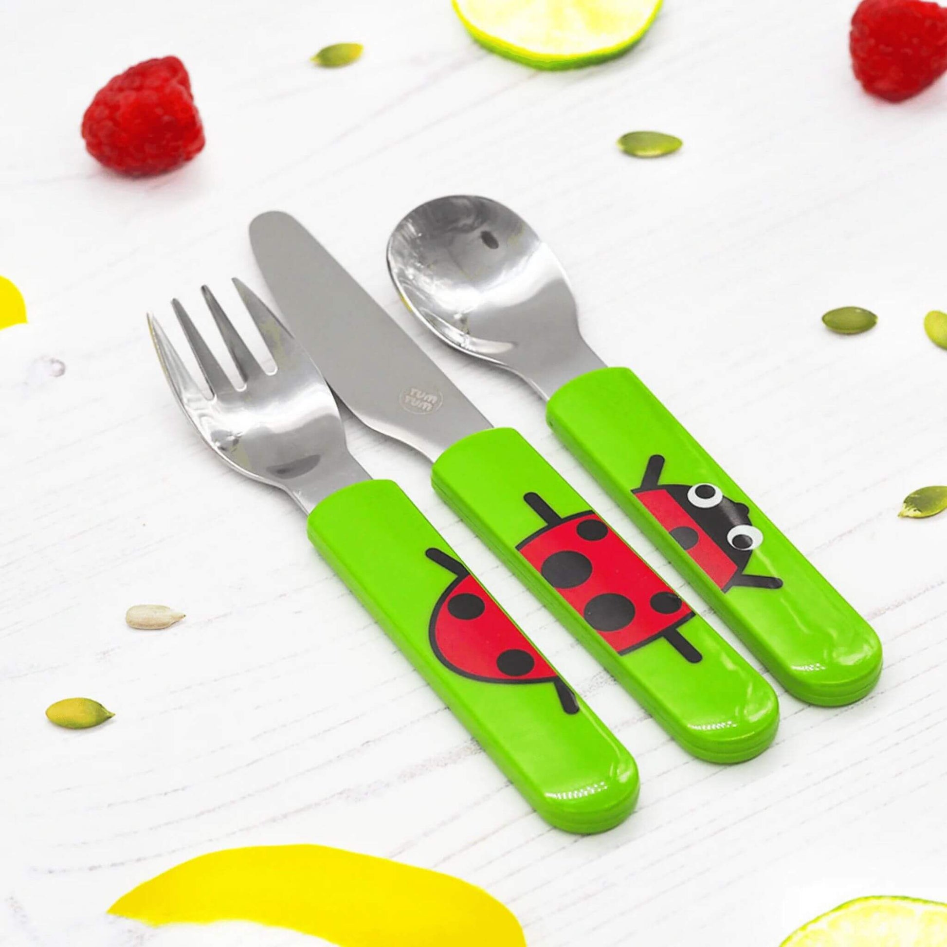 A toddler's cutlery Set, featuring a spoon, knife, and fork with bright green handles and a cute ladybird design. 