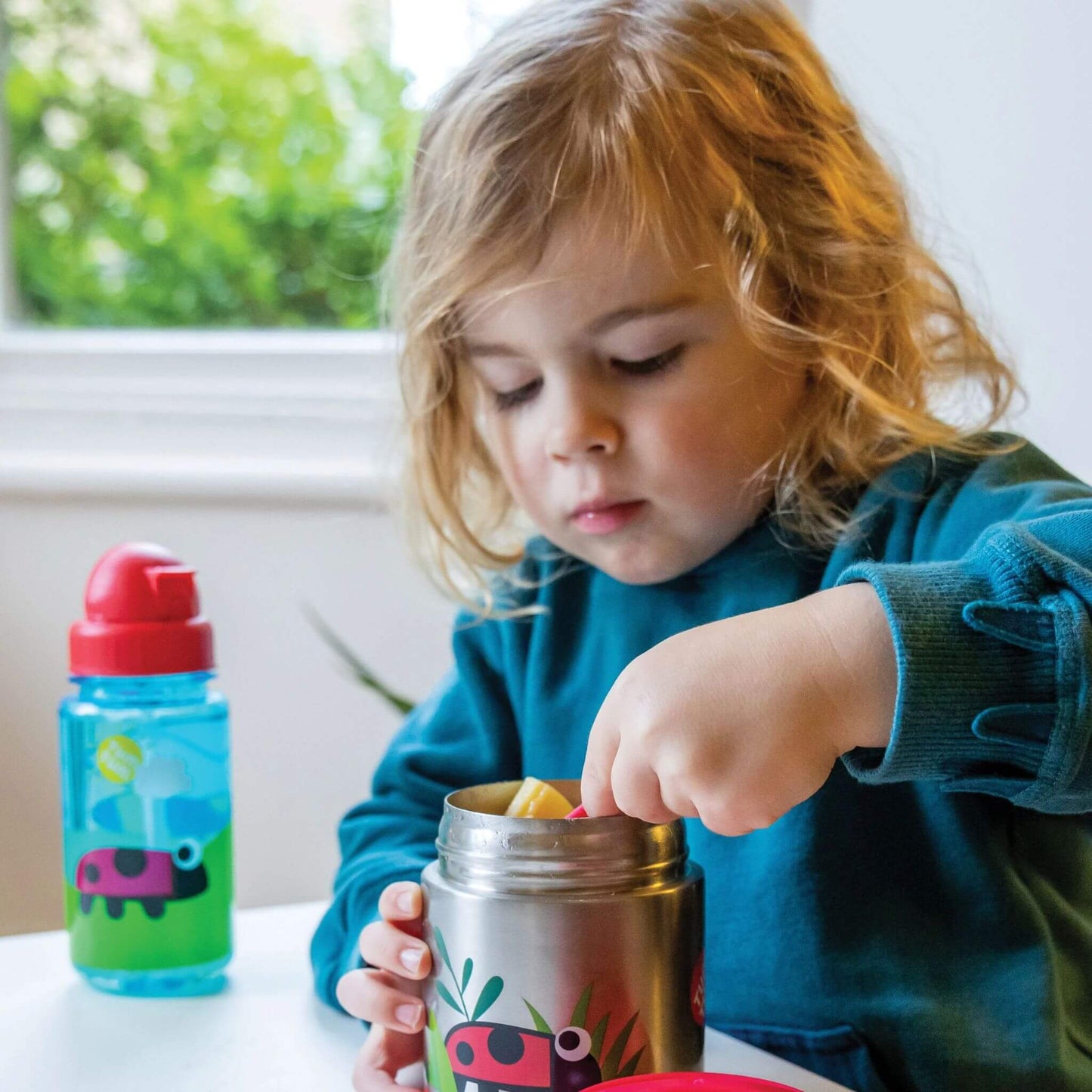 Child eating from an insulated food flask, with a red spork. Perfect for hot or cold meals.