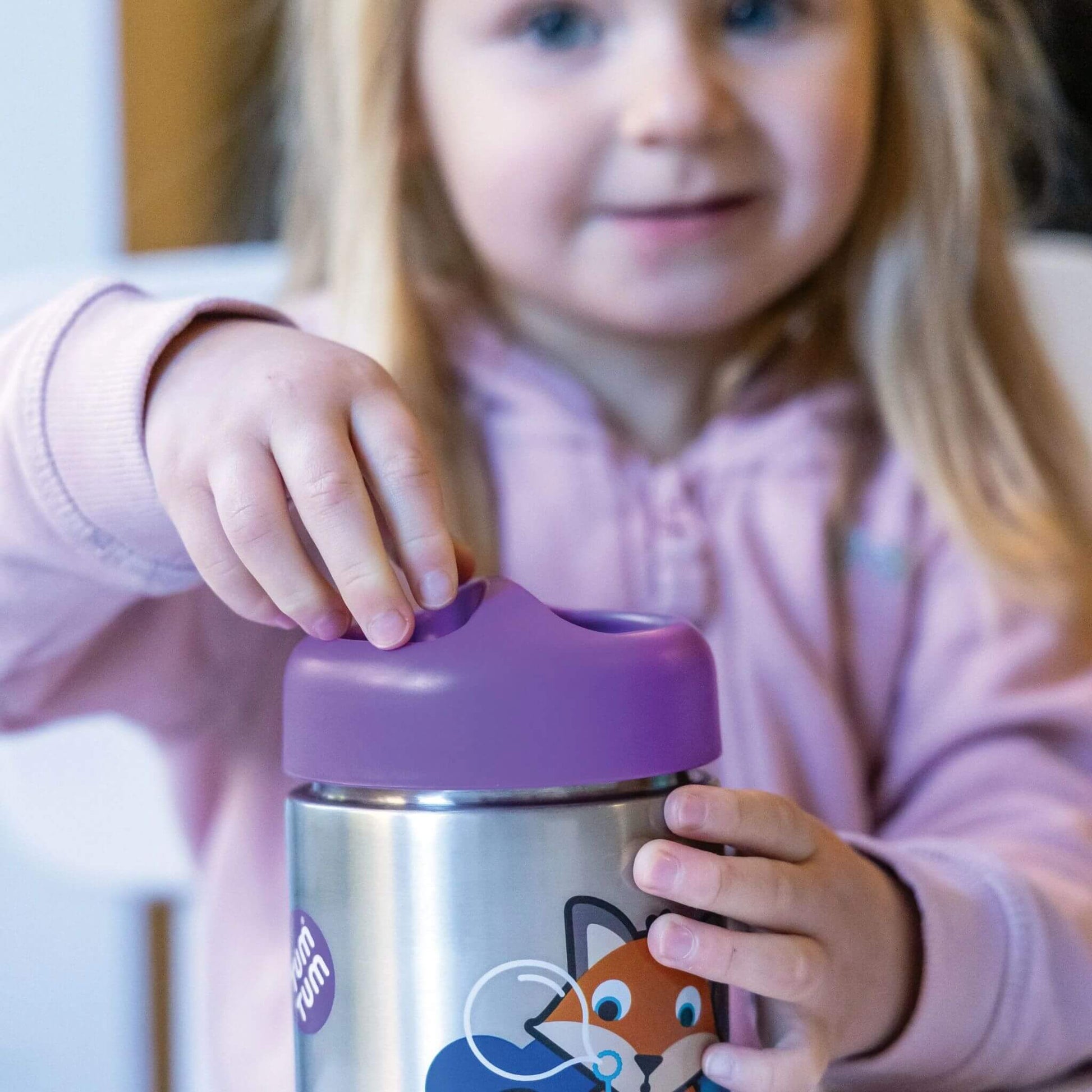 Child opening  an insulated food flask with purple lid and fox character design, perfect for keeping food hot or cold, with easy-to-use design for little hands.