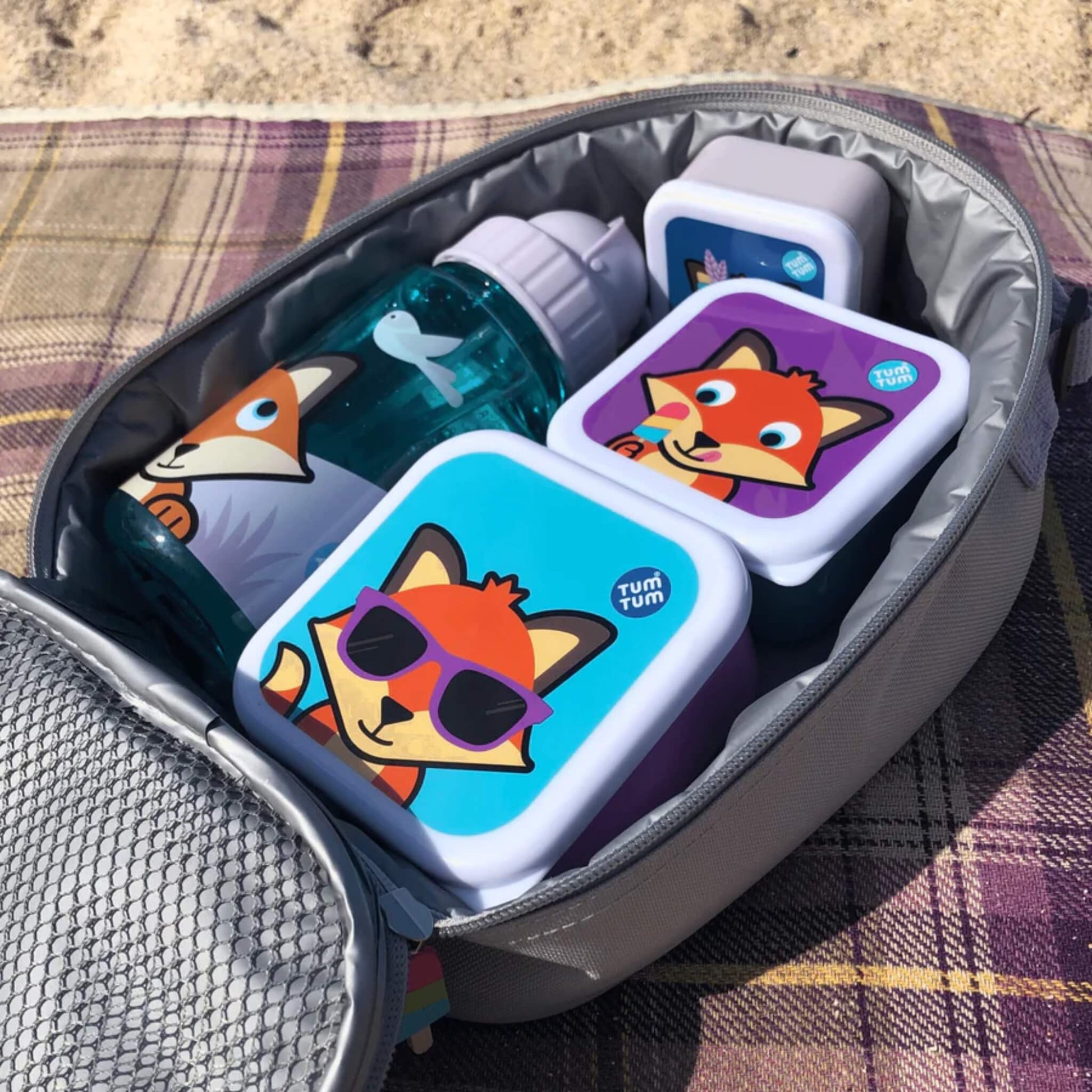 An open insulated lunch bag showing a water bottle and stacked snack boxes packed neatly inside.