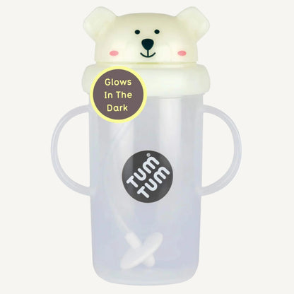 A clear handled large sippy cup with a pale glow-in-the-dark flip-top lid, bear character design, and an internal weighted straw visible inside the cup.