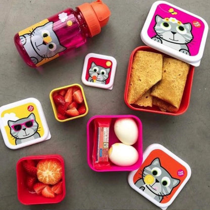 A set of cartoon cat-themed lunch containers and a matching bottle arranged on a grey surface, filled with snacks including crackers, strawberries, an orange slice, and hard-boiled eggs.
