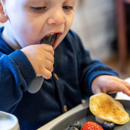 Toddler using silicone fork to eat pancakes and fruit, perfect for self-feeding and promoting independent eating skills.
