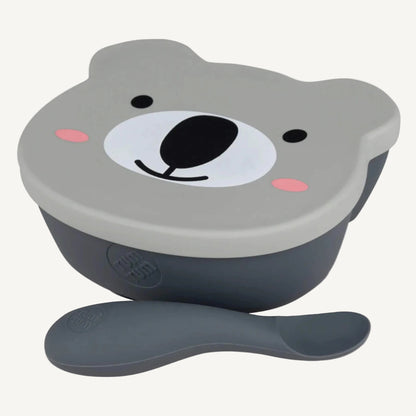A silicone suction bowl with a bear-shaped lid and matching spoon, shown from a slightly angled top view with the spoon placed in front.