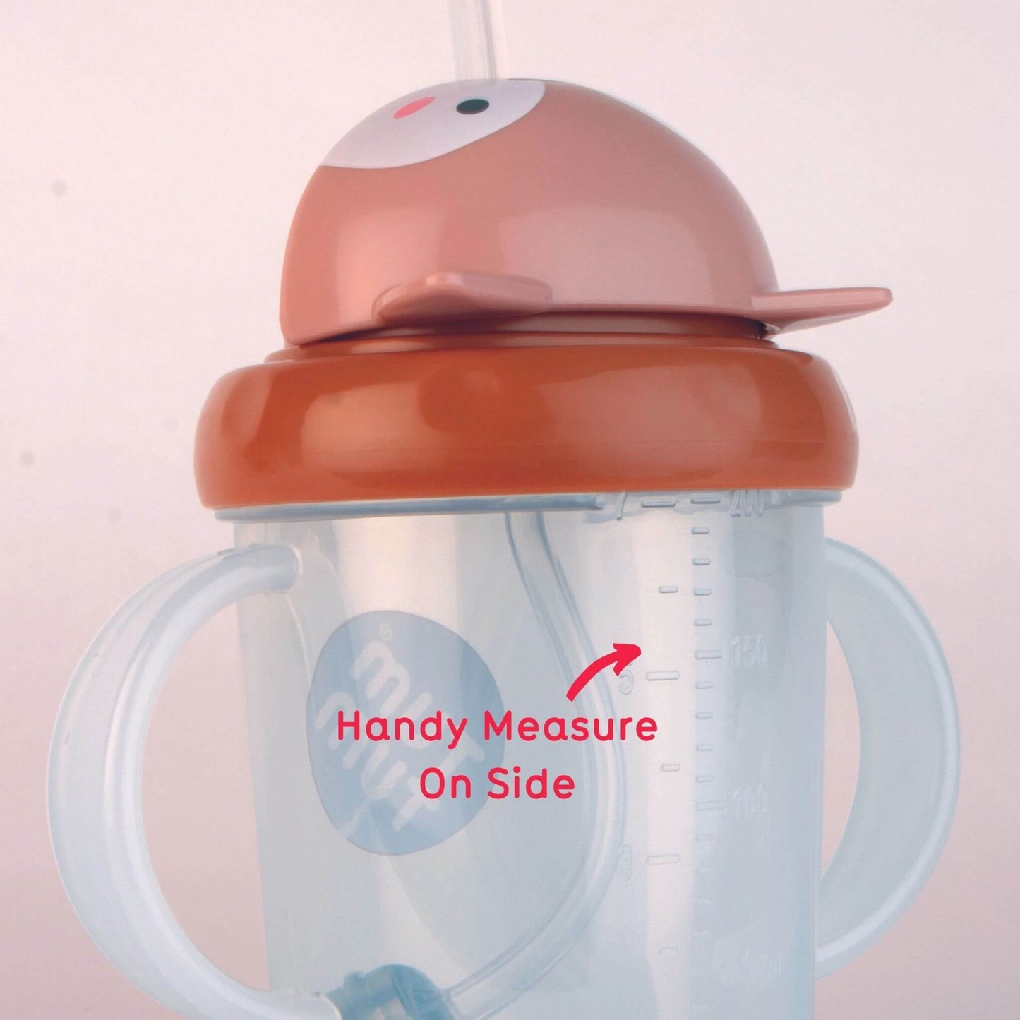 Close-up of a clear handled straw cup with a brown lid and a pink fox character top, showing red text reading “Handy Measure On Side” with an arrow pointing to raised measurement markings on a clear cup.