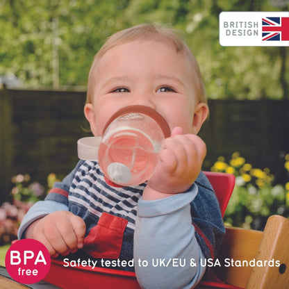 Child holding a brown sippy cup outdoors with 'British Design' and 'BPA free' text.