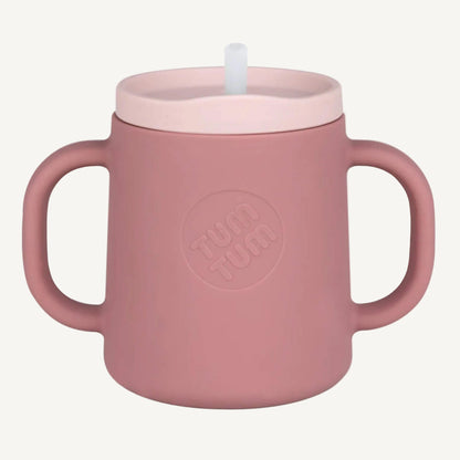 A pink silicone trainer cup with two handles and a straw lid, shown from the front to highlight the cup shape and grip.