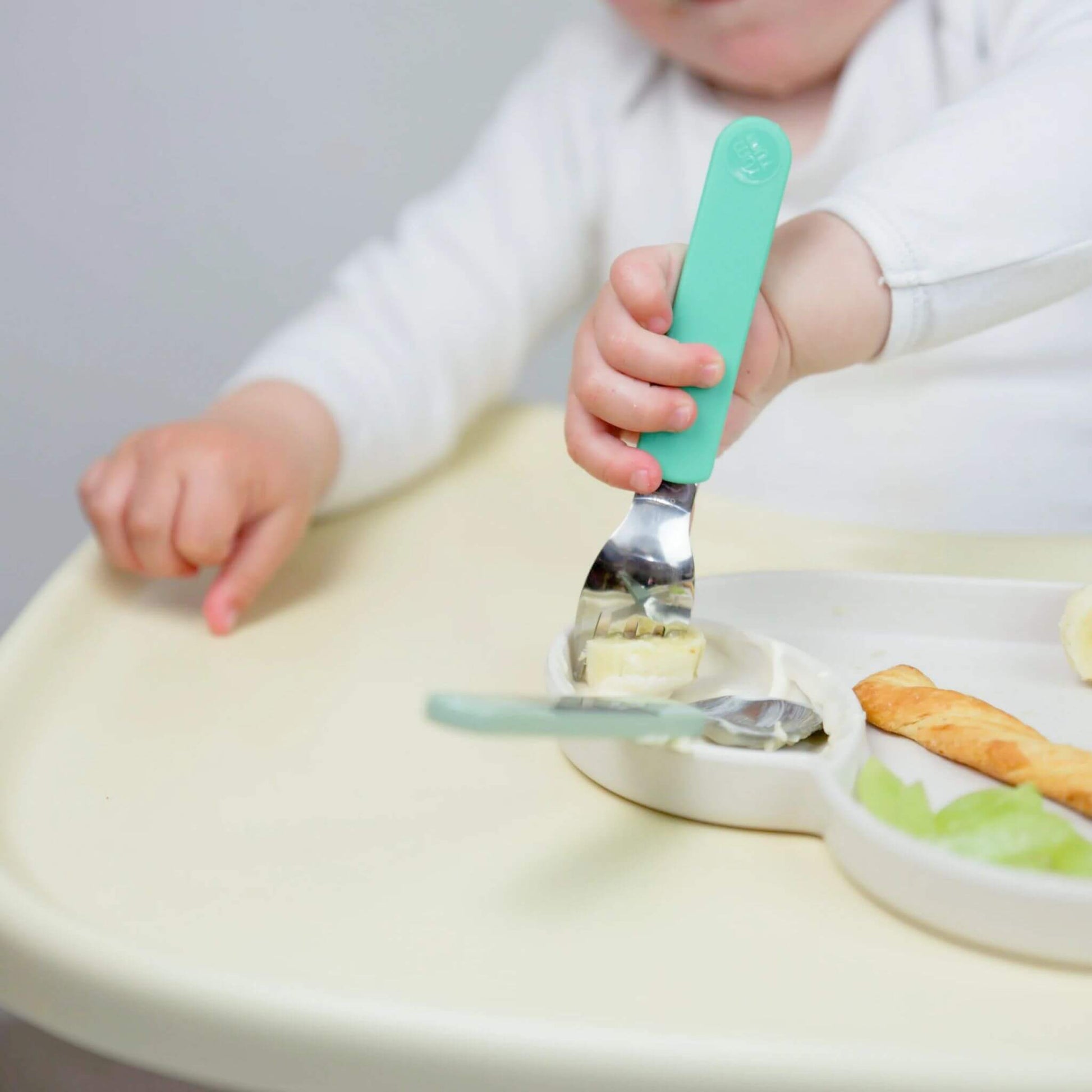 A child using a toddler fork to eat, holding the fork with a comfortable grip. Designed for self-feeding, featuring Stanley Sloth handles.