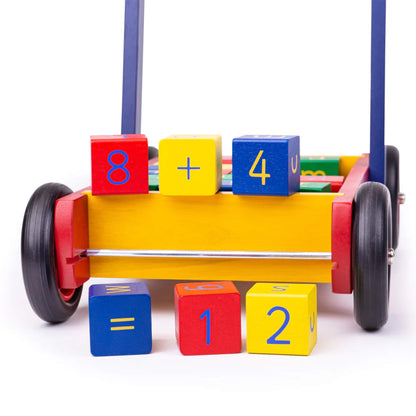 Close-up of blocks arranged to show the equation “8 + 4 = 12” beside the walker’s front wheels.