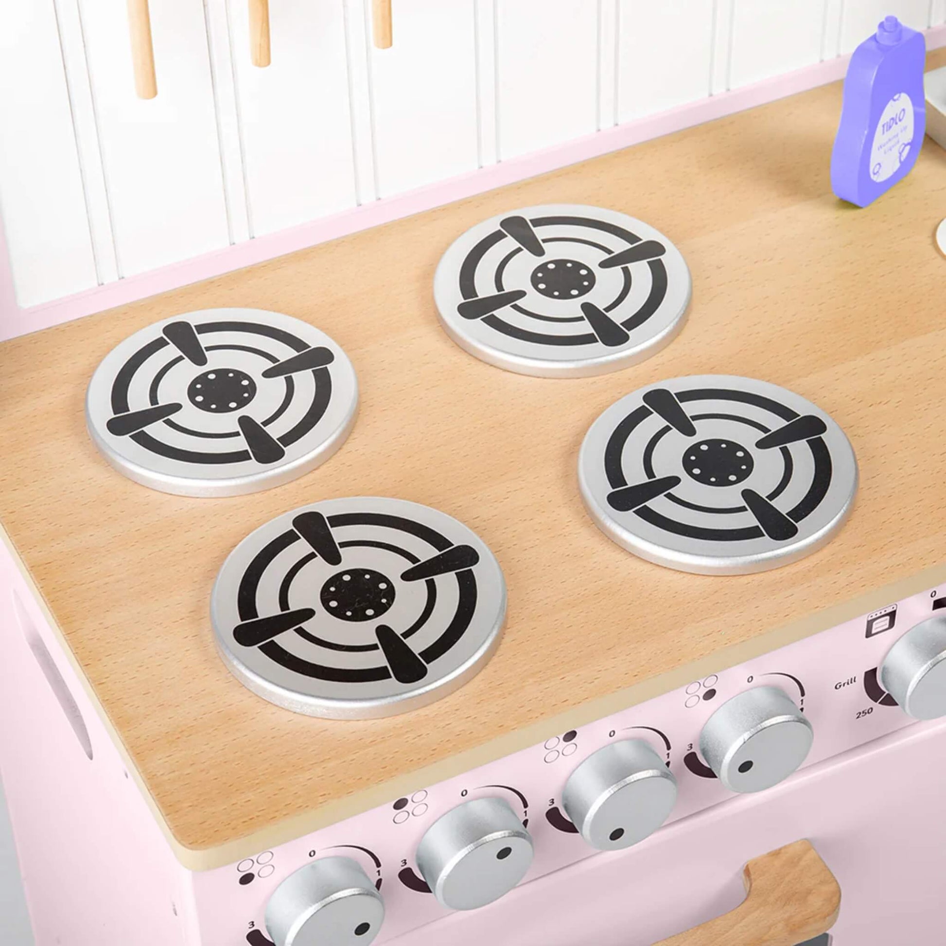 Four round burner plates set into a wooden countertop with a bottle of pretend washing-up liquid beside the sink.