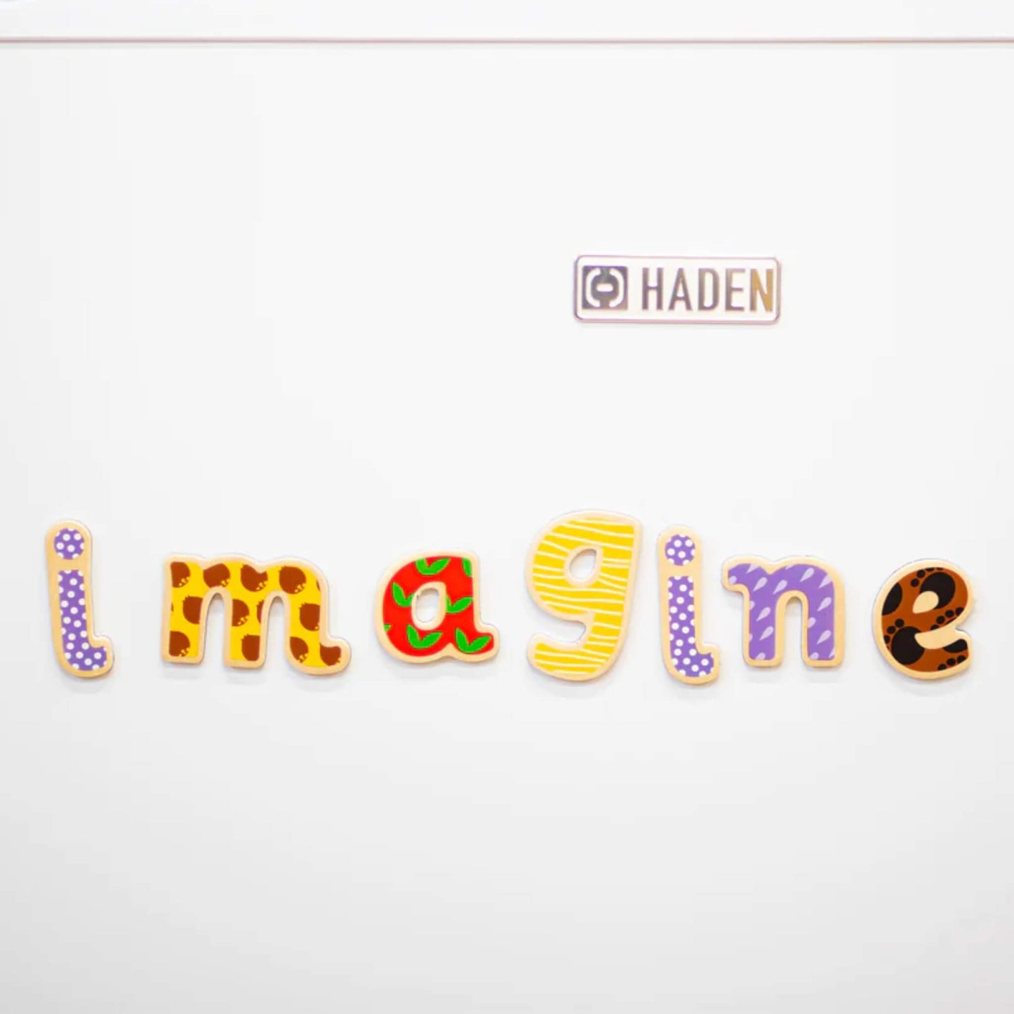 Close up of the word 'Imagine' spelt using wooden magentic letters placed against a white background.