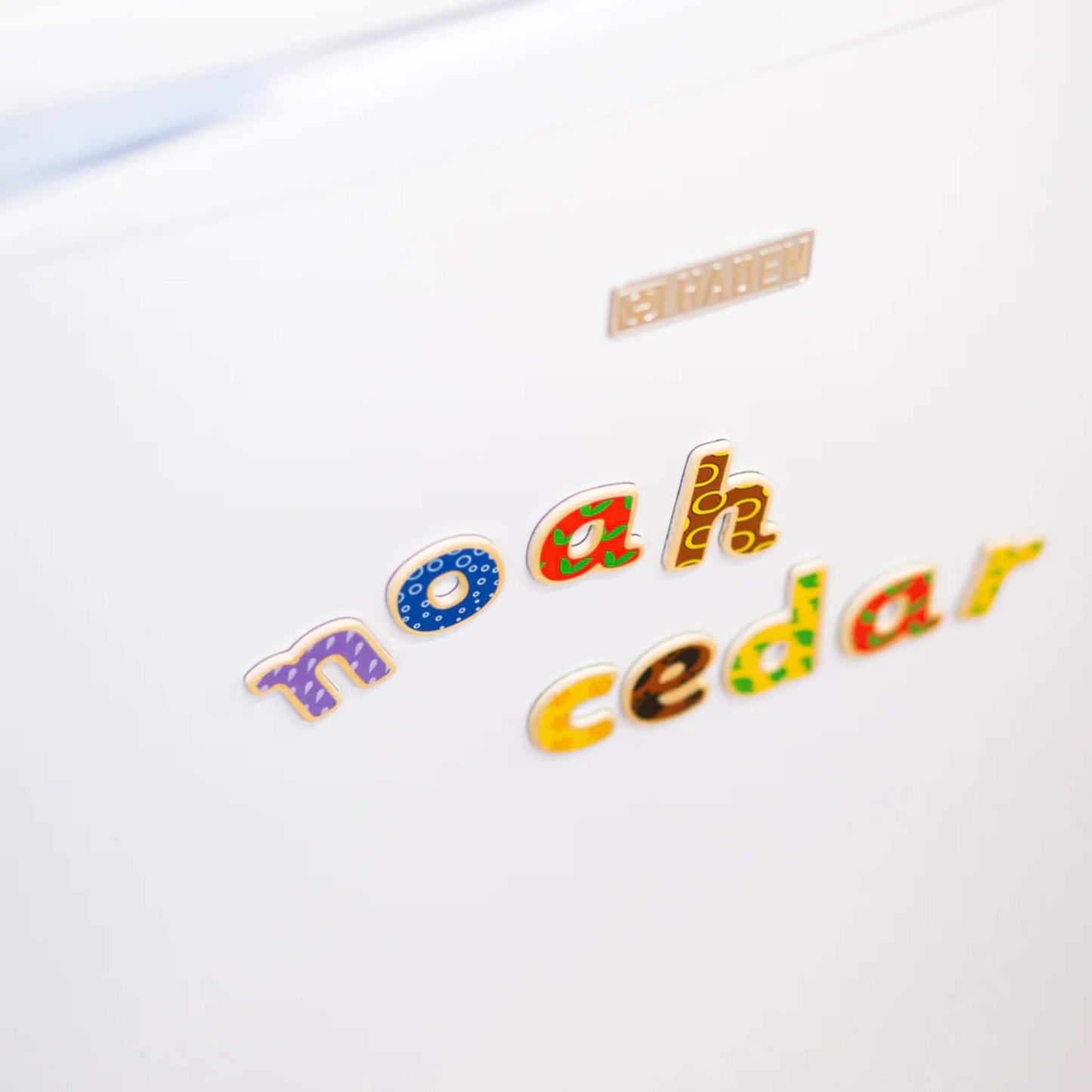 Colourful wooden magnetic lowercase letters spelling 'noah' 'cedar' on a white background.