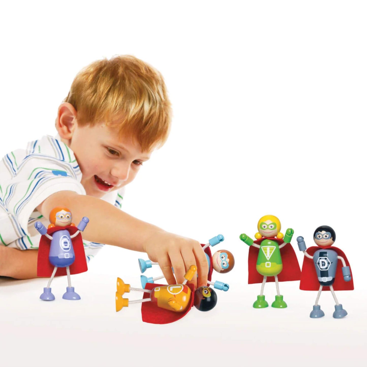 Child playing with the Tidlo superhero figures, arranging them on a white surface during imaginative play.