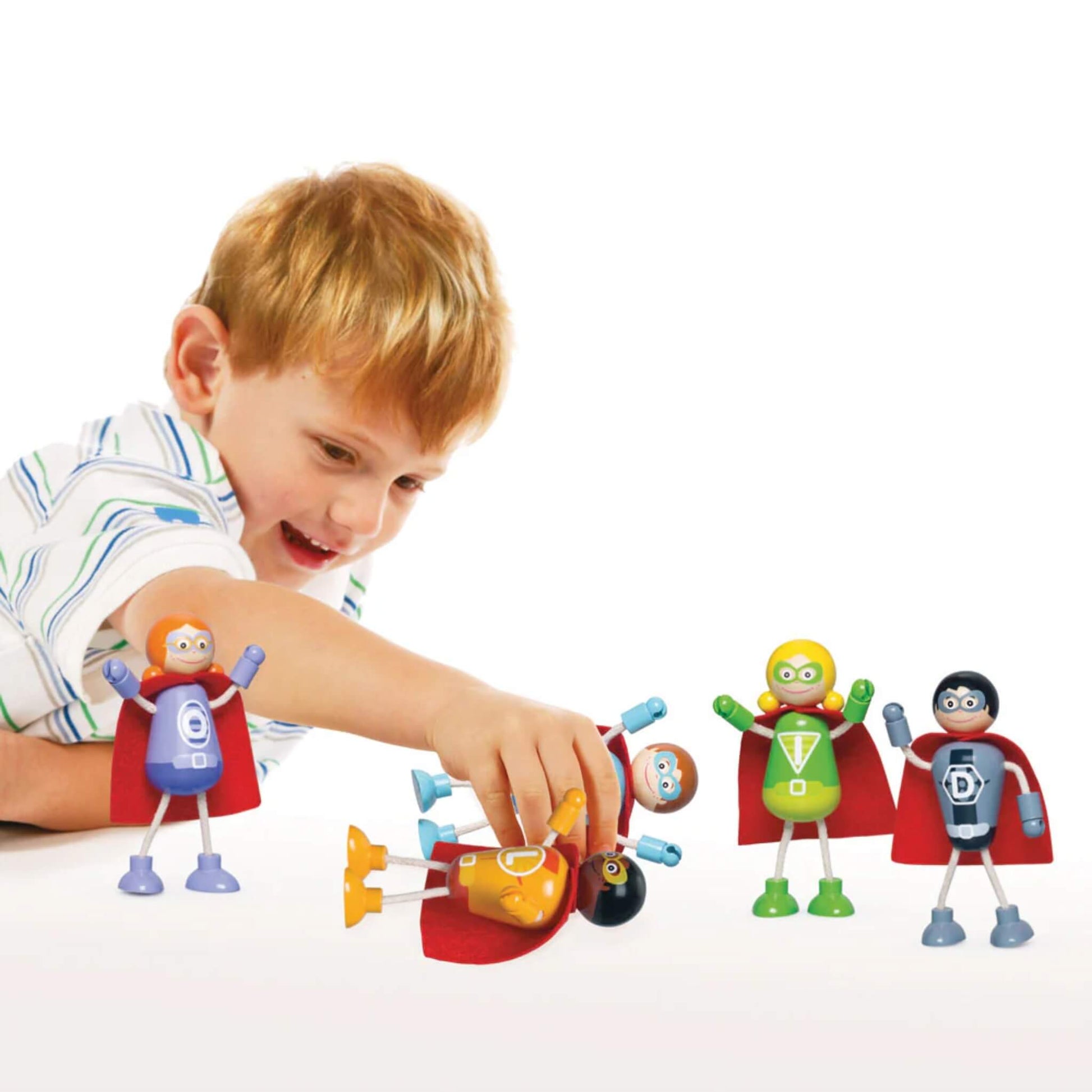 Child playing with the Tidlo superhero figures, arranging them on a white surface during imaginative play.