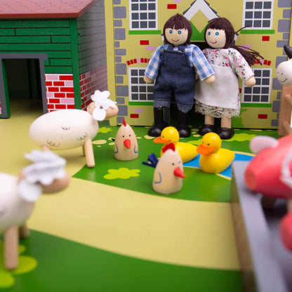Two wooden farmer figures standing outside the farmhouse at Tidlo Oldfield Farm, surrounded by chickens, ducks and sheep in a colourful play scene.