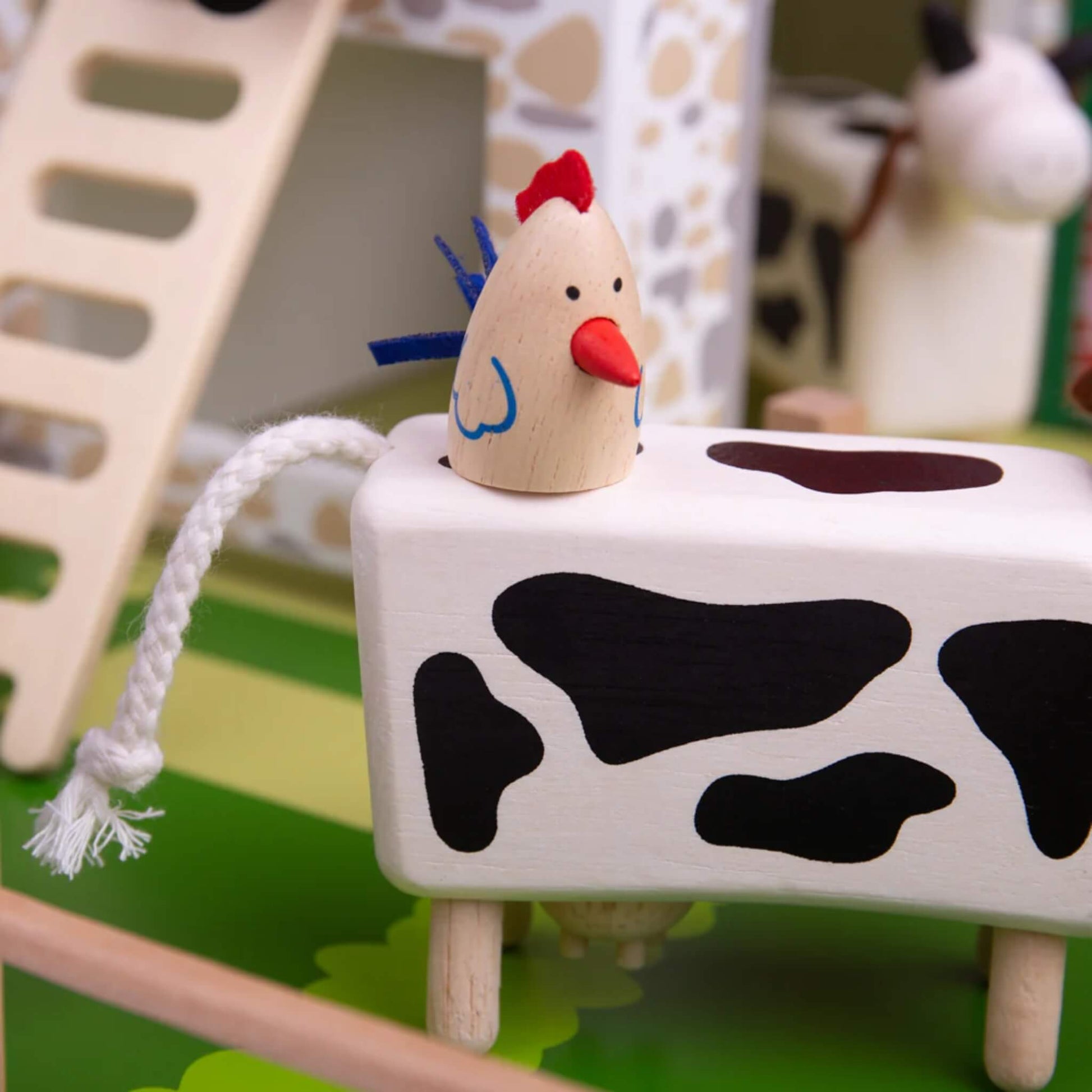 Chicken balanced on a cow’s back at Tidlo Oldfield Farm, with a rope tail and painted wooden details shown clearly in the paddock area.