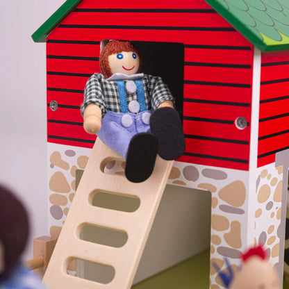 Wooden farmer figure sitting at the top of the barn ladder at Tidlo Oldfield Farm, with the red and stone-painted barn in the background.