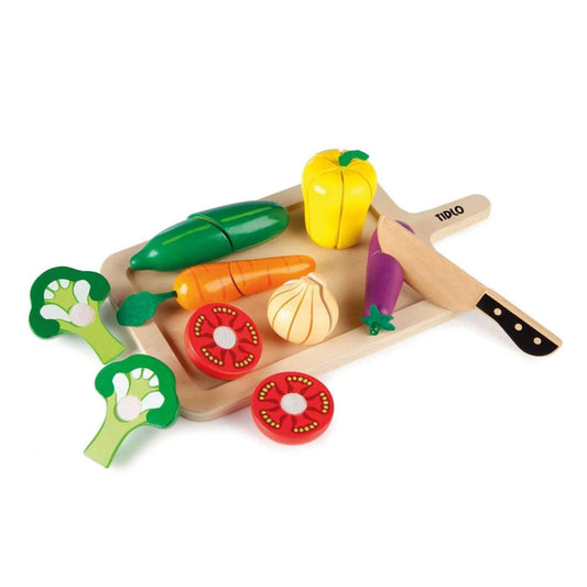 Tidlo Cutting Vegetables Set wooden pretend play food arranged on a chopping board with toy knife, including broccoli, carrot, pepper, aubergine, tomato slices and onion pieces.