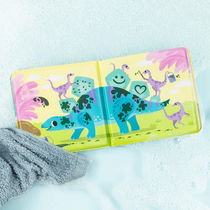 Inside spread of the bath book showing a blue dinosaur with dark muddy spots being cleaned by playful purple dinosaurs in a bubbly bath scene.