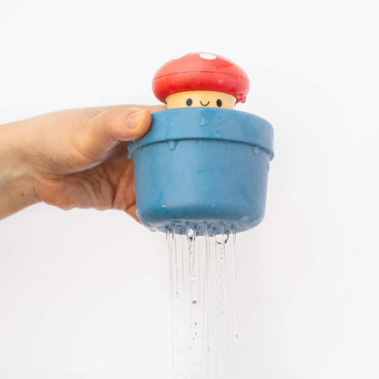 Close-up of a hand lifting the blue bath toy above the tub as water streams out from the base.
