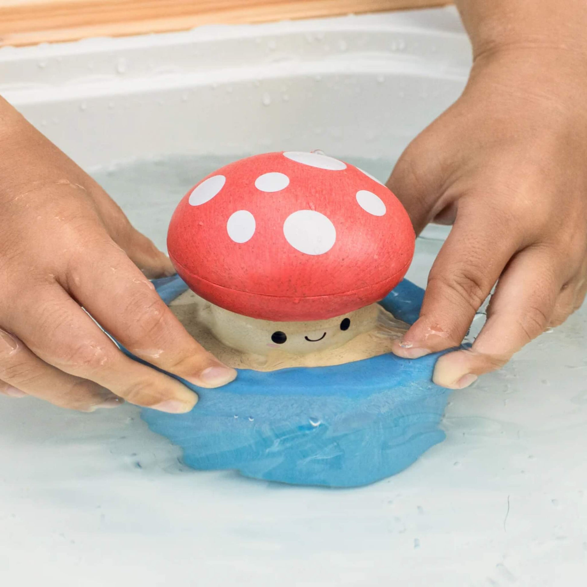 Child pressing the toy into a shallow tub of water, causing the character to pop up.