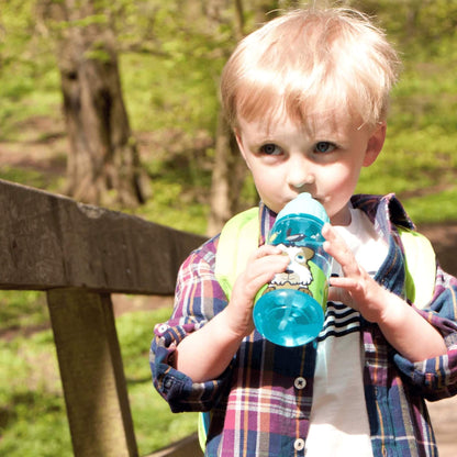 Child drinking from a blue drinks bottle outdoors.