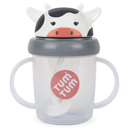 A clear plastic sippy cup with two handles, a grey lid, and a cow-themed lid featuring a white and black cow face with a pink nose. A straw is inside, and a red circular 'TUM TUM' logo is printed on the front.