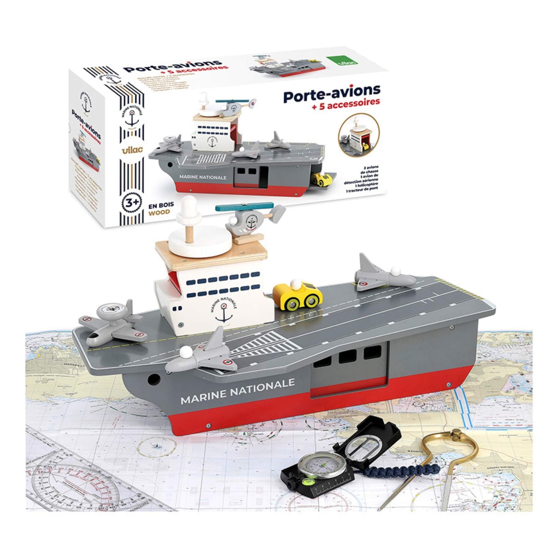 A wooden aircraft carrier toy on nautical charts with aircraft, a helicopter, and a yellow deck vehicle on deck. Packaging shown nearby.