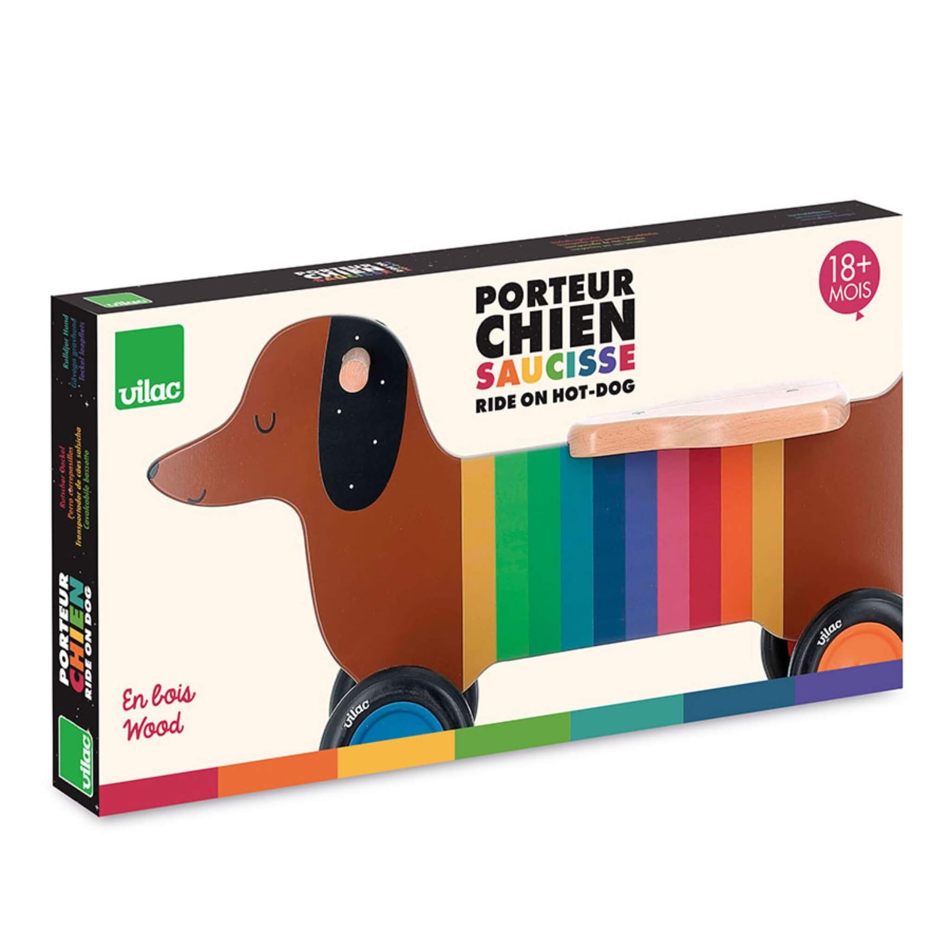 A close-up of packaging for a wooden dog ride-on toy showing illustrated dachshund design with rainbow stripes and product details on the box.