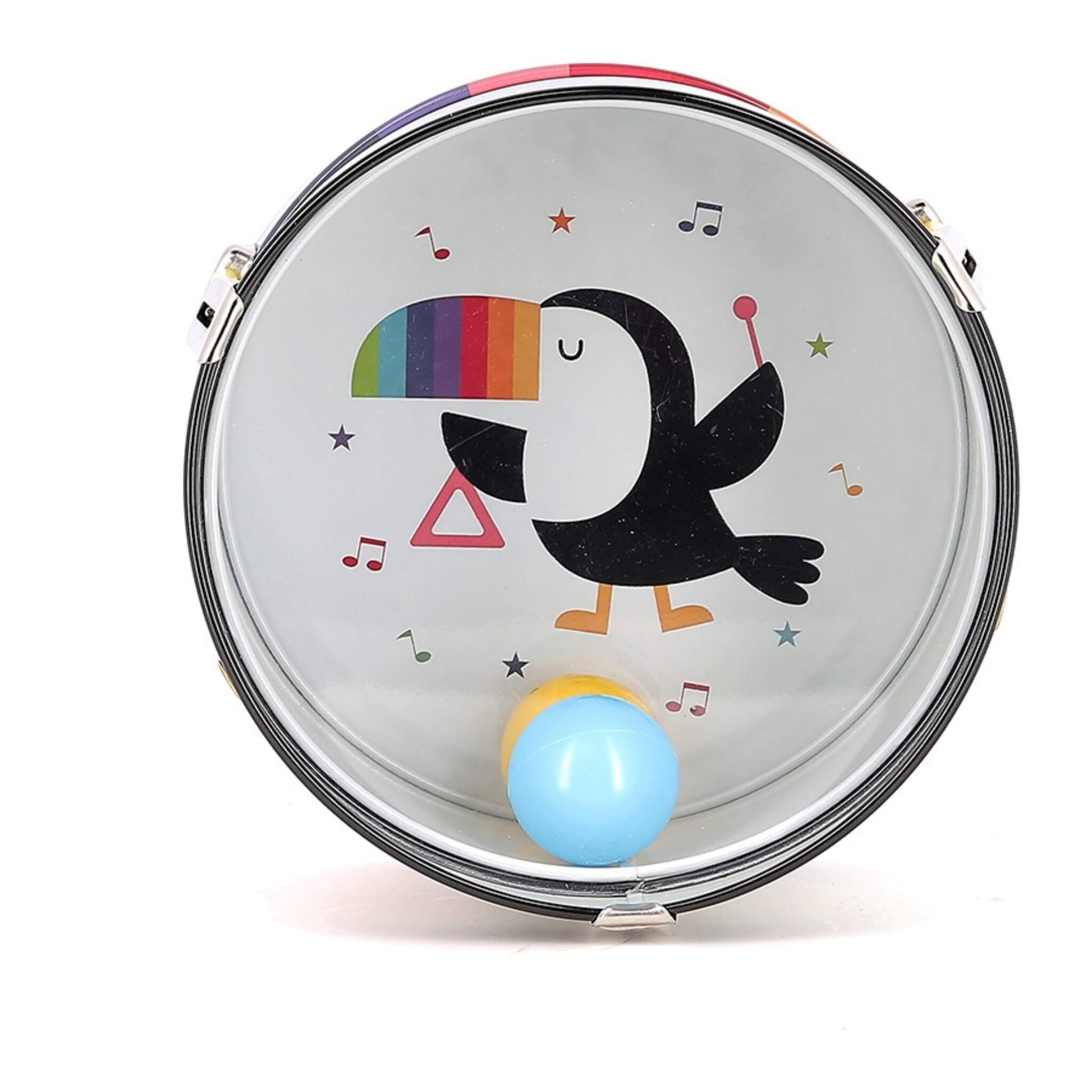 A close-up of a metal drum head featuring a toucan illustration with a rainbow beak, musical notes, and two plastic balls resting at the base.