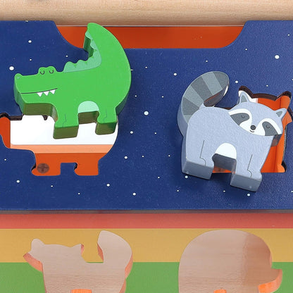 Close-up of a green crocodile and grey raccoon wooden block fitted into starry blue roof slots of a shape sorter.
