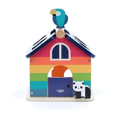 Front view of a rainbow-coloured wooden shape sorter with a blue toucan figure on the roof and a panda at the doorway.