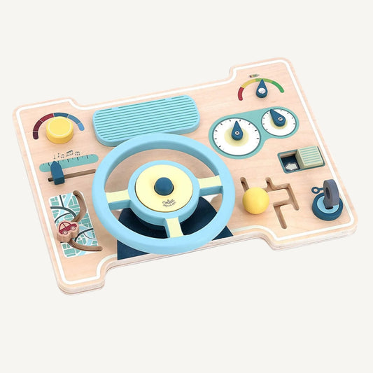Wooden activity board styled as a car dashboard with steering wheel, sliding controls, dials and tactile elements in soft blue and yellow tones.