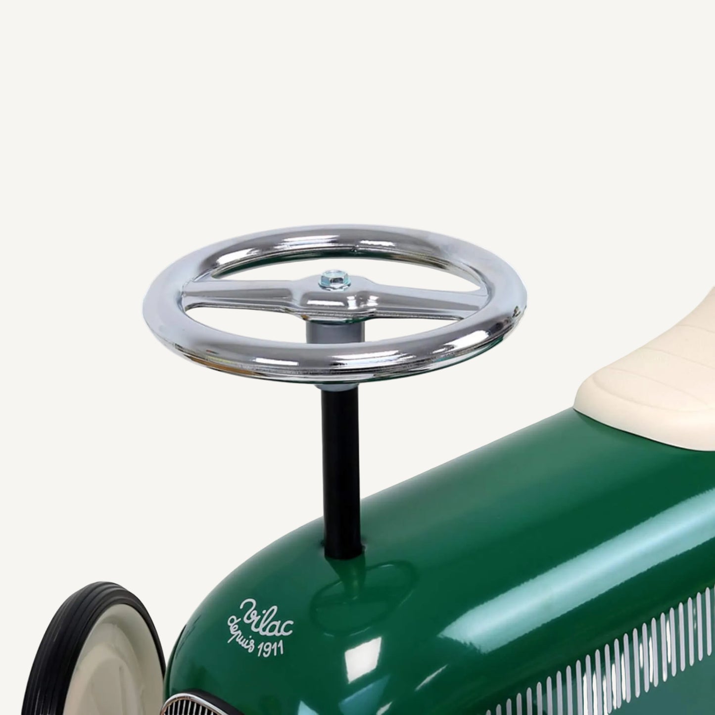 A close-up of a round chrome steering wheel attached to a black vertical column on top of a green metal ride-on toy car.