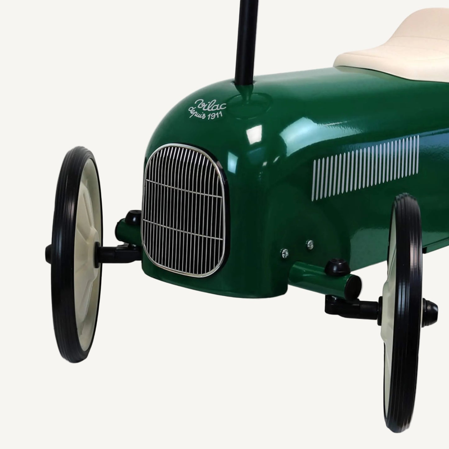 A close-up of the front of a green ride-on toy car showing a chrome grille, front axle, wheel and the lower edge of the body.