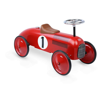 A red metal ride-on car shown at an angle, with a brown seat, chrome steering wheel and large red wheels.