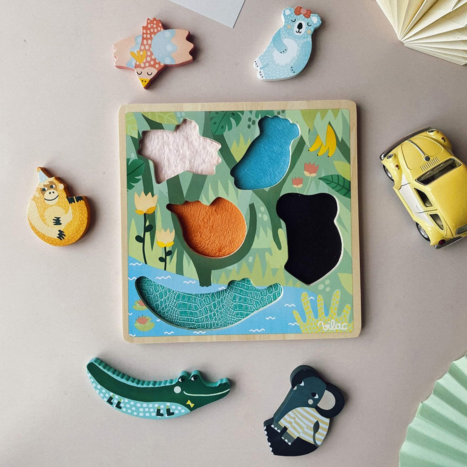 A Touch and Feel Puzzle displayed with colourful wooden animal pieces and a tactile jungle-themed board on a table.