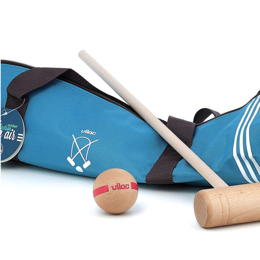 A close-up of a kids wooden croquet mallet and red-striped ball placed beside a blue fabric carry bag.