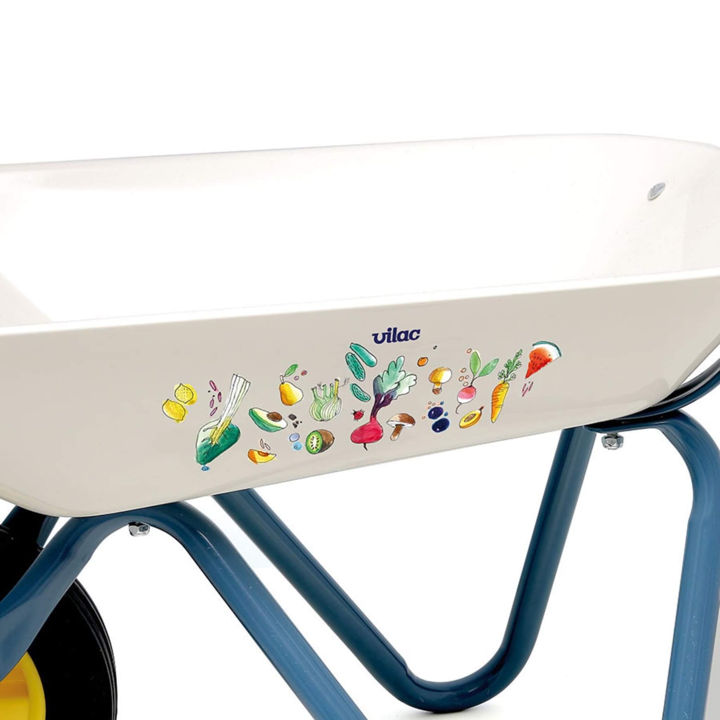 A close-up of a toy wheelbarrow tray featuring illustrated vegetables and garden produce design on a white metal surface.