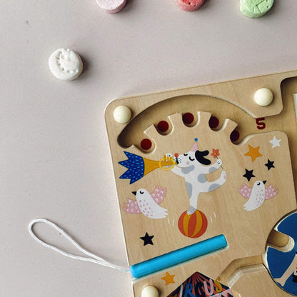 Close-up of the top left corner of the circus magnetic maze, showing a performing dog blowing a trumpet while balancing on a ball, with doves flying around.