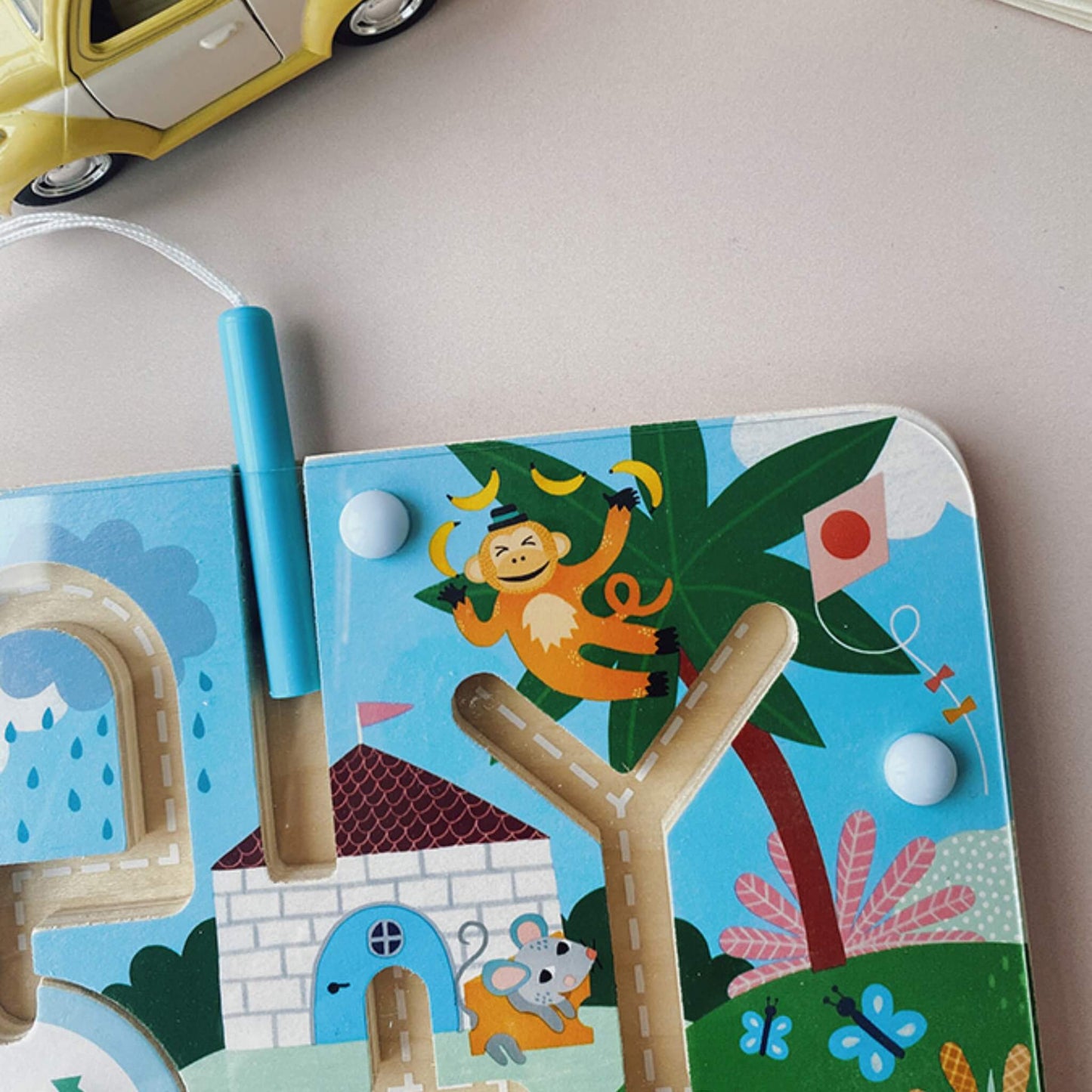 Close-up of the top right corner of the maze, showing a monkey in a tree with bananas, a mouse outside a house, and coloured beads on the tracks.