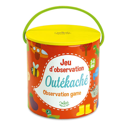 Close-up of the cylindrical red storage box with yellow lid and green handle, decorated with playful illustrations and labelled ‘Jeu d’observation Outékaché’.