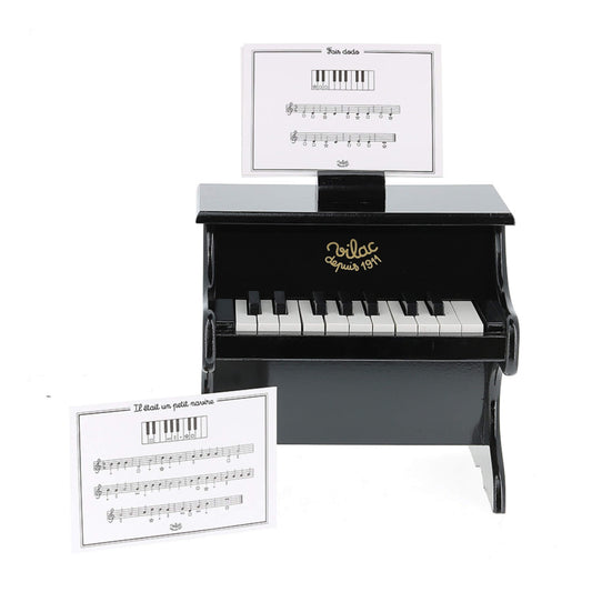 Front view of a small black wooden toy piano with white and black keys, featuring a music score card resting on a holder above the keyboard.