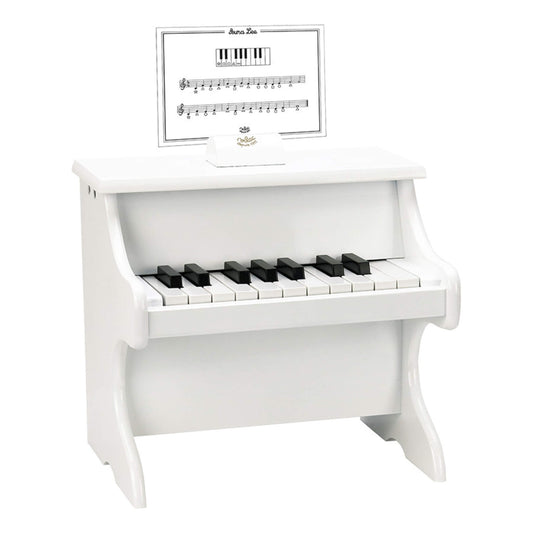 Small white wooden upright toy piano with black and white keys and a simple music score card placed on the holder.