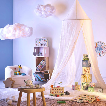Playroom scene with nesting blocks stacked inside a canopy tent, surrounded by toys, books and soft lighting.