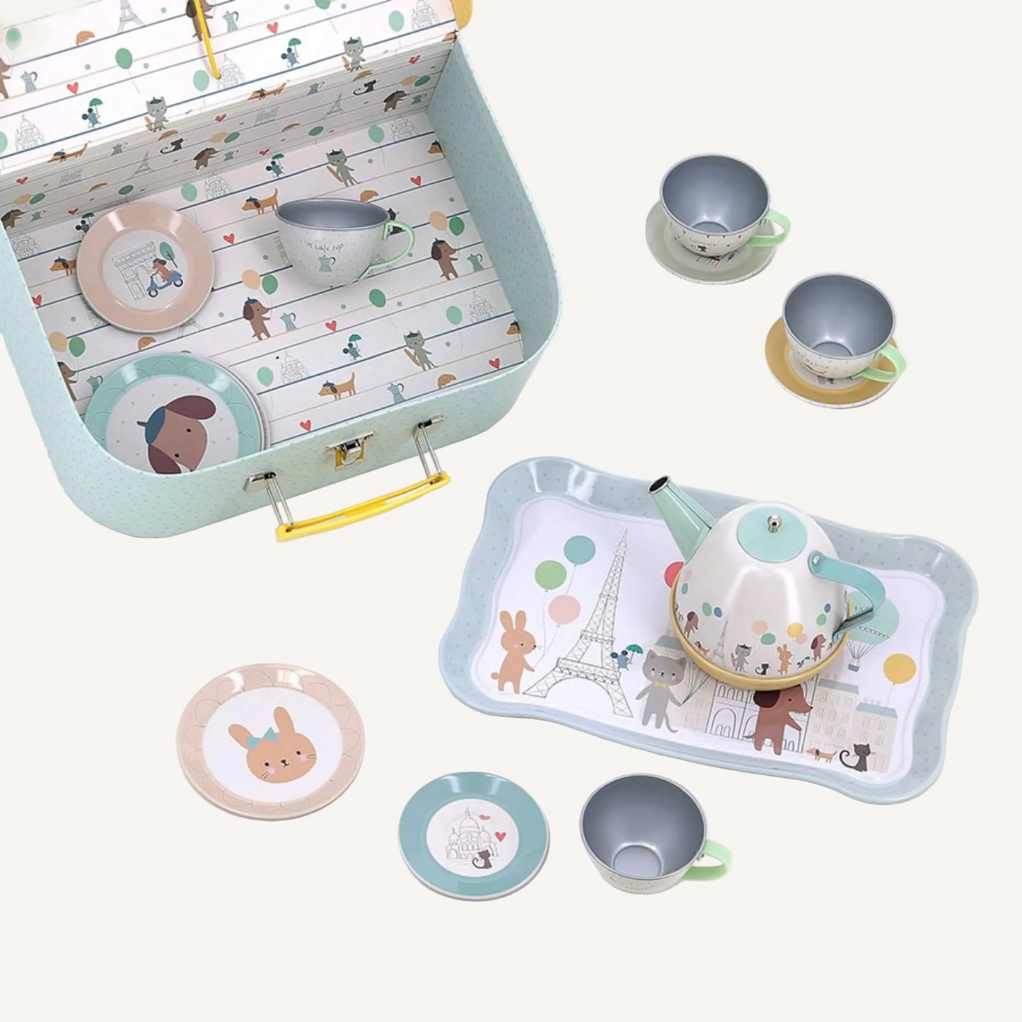 Open pastel suitcase showing Paris themed tea set pieces including teapot, tray, cups and saucers inside.